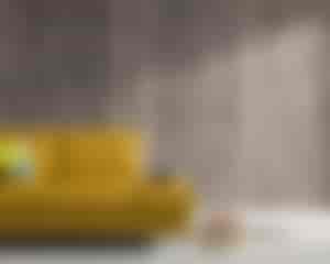 Hintergrundwand vor der gelben Sofa aus imi  Altholz grau mit einem natürlichen Aussehen.