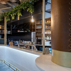 Bar in Restaurant mit Barfläche aus STARON Supreme Morning Sky und hockern mit dunkelbraunem Leder
