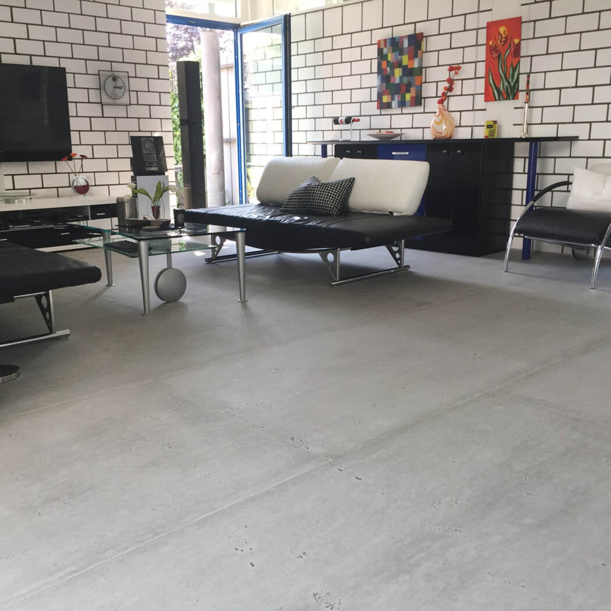 Wohnzimmer mit schwarzen Ledercouches; Boden in imi Matte vintage